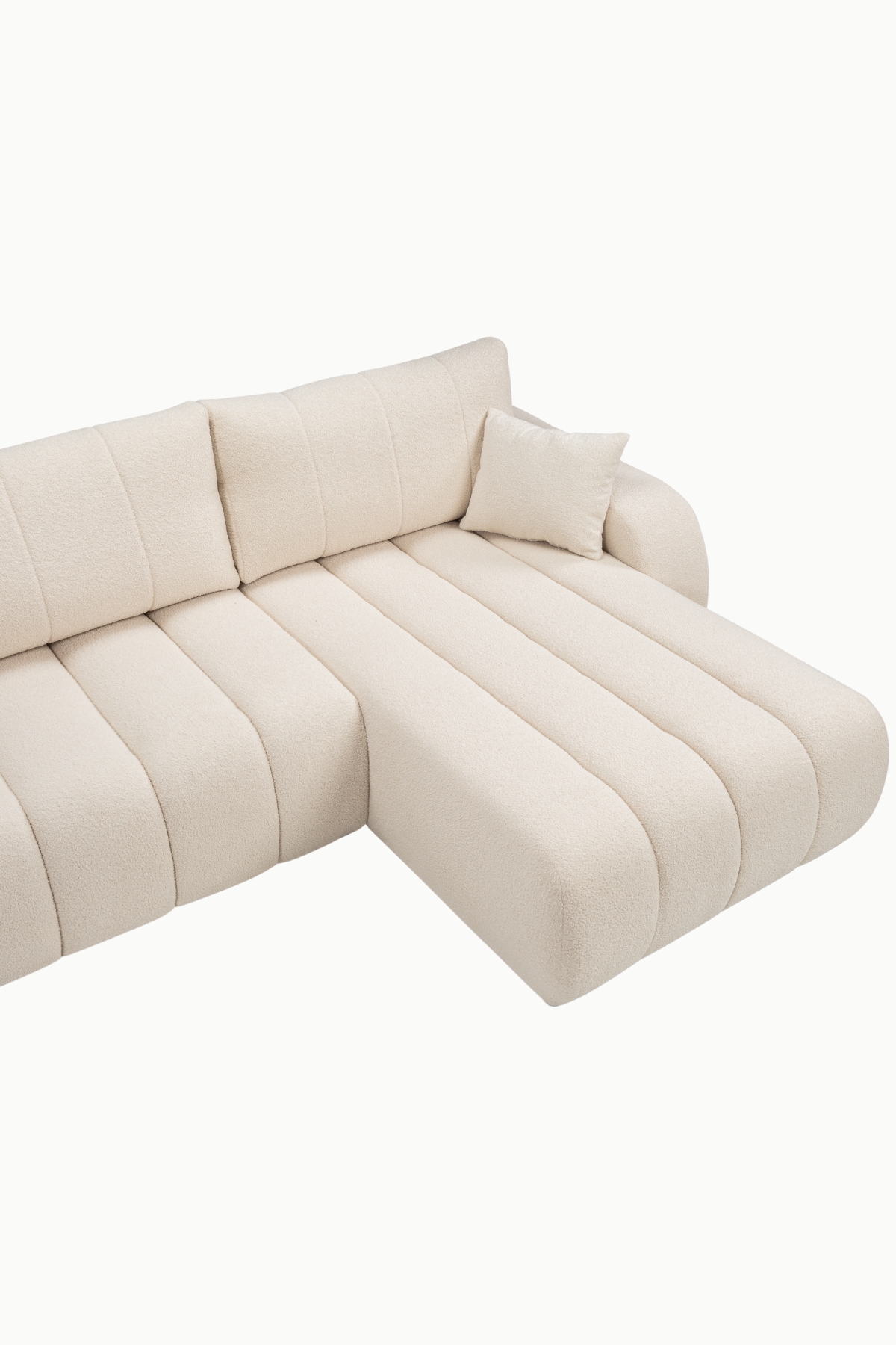 Canapé d’angle Baloo coffre et convertible en laine bouclée écrue, assises larges à coutures verticales, dossier confortable et méridienne, design arrondi moderne.